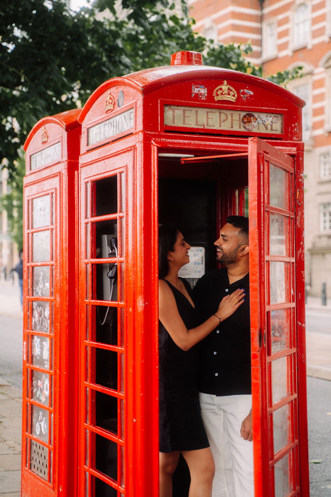 Couple laughing inside a red phone box