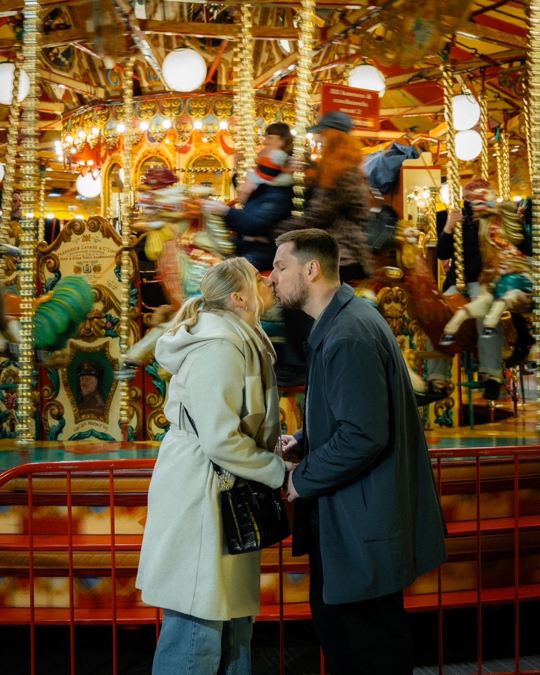 Couple kissing in front of a carousel