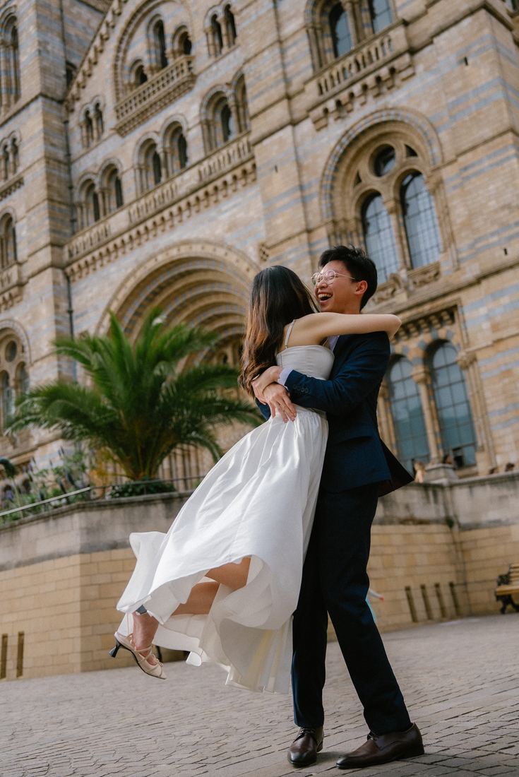 Groom lifting the bride in front of the Natural History Museum