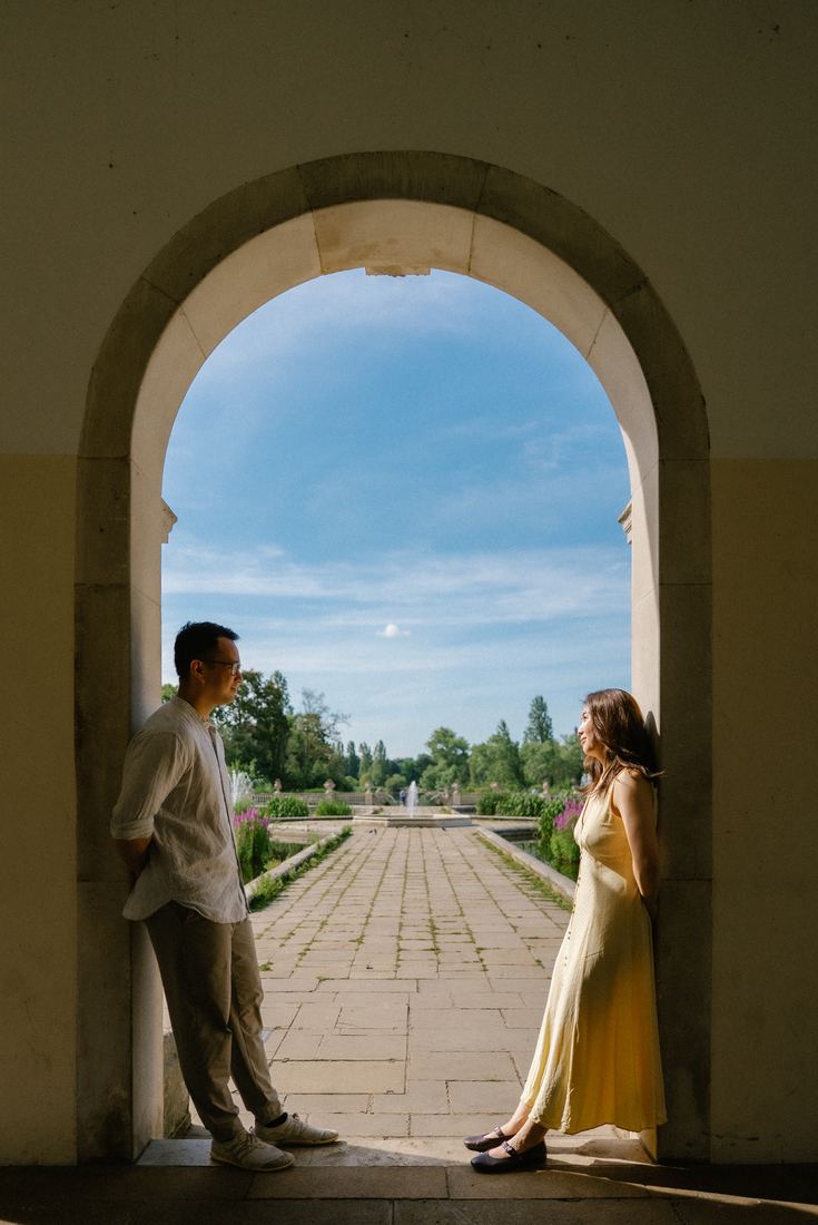 Couple framed by a stone archway overlooking a garden