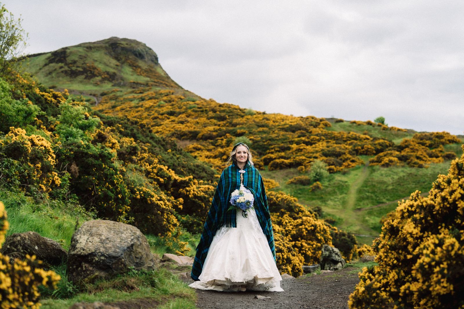 Bride standing among yellow gorse on Arthur's Seat