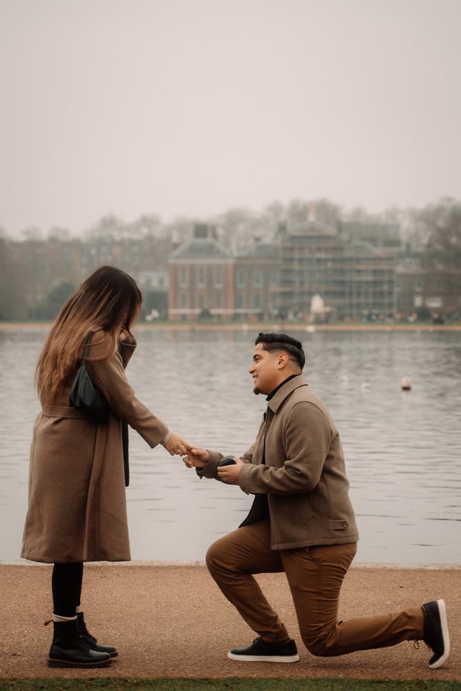 Man proposing on one knee by a lake
