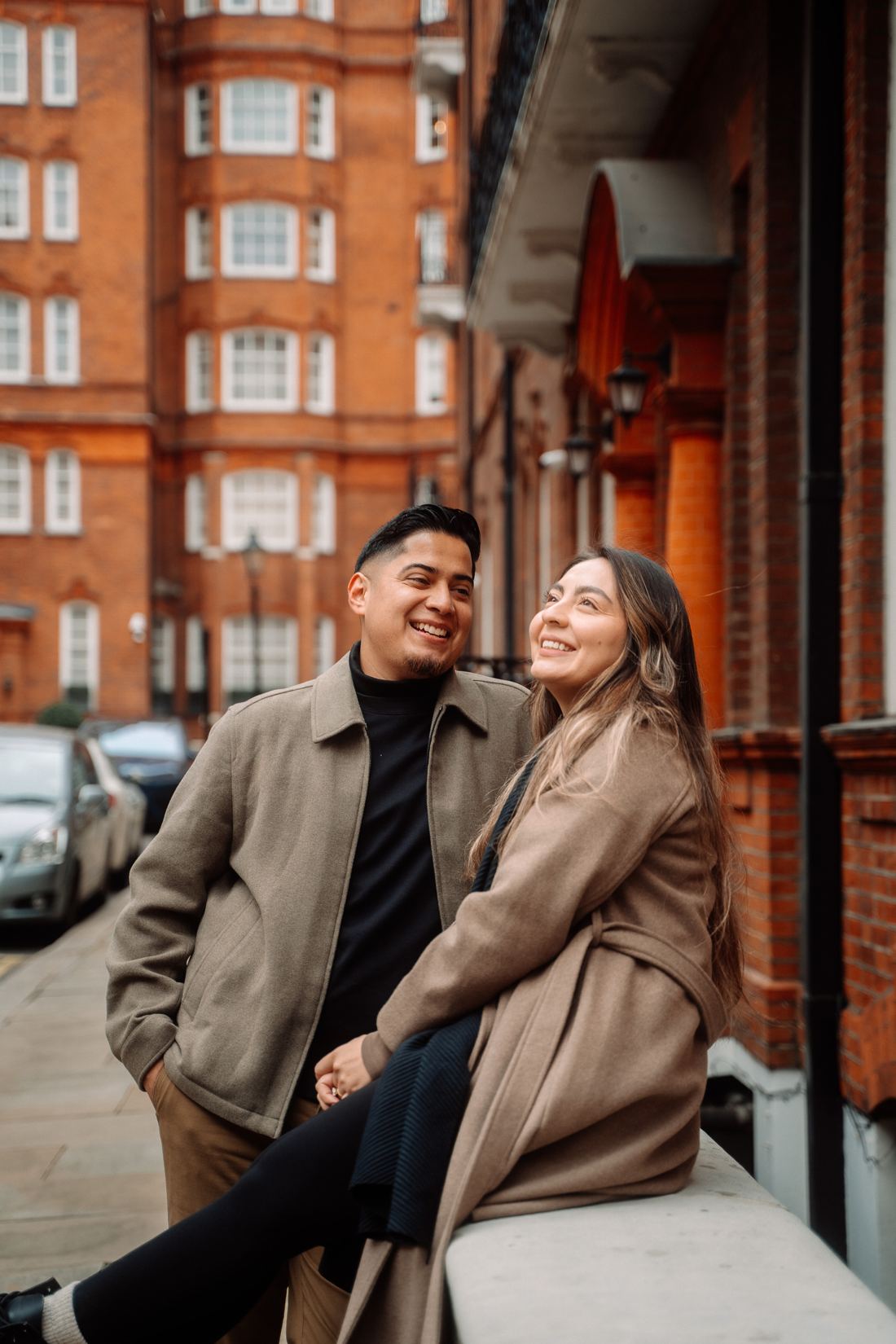 Couple laughing against a red-brick London street