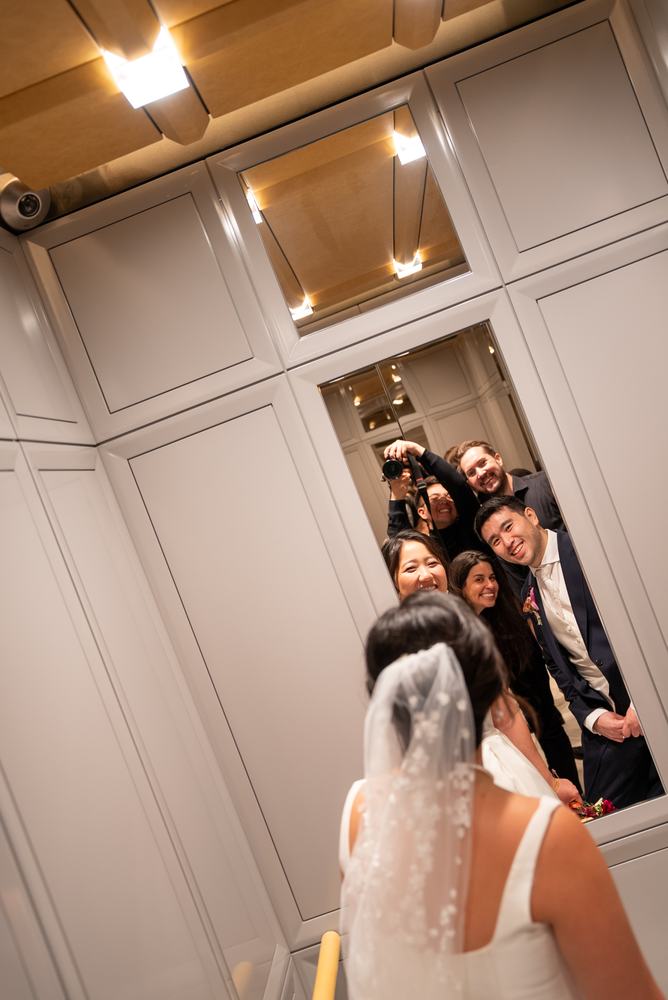 Friends crowding into a mirror to see the bride