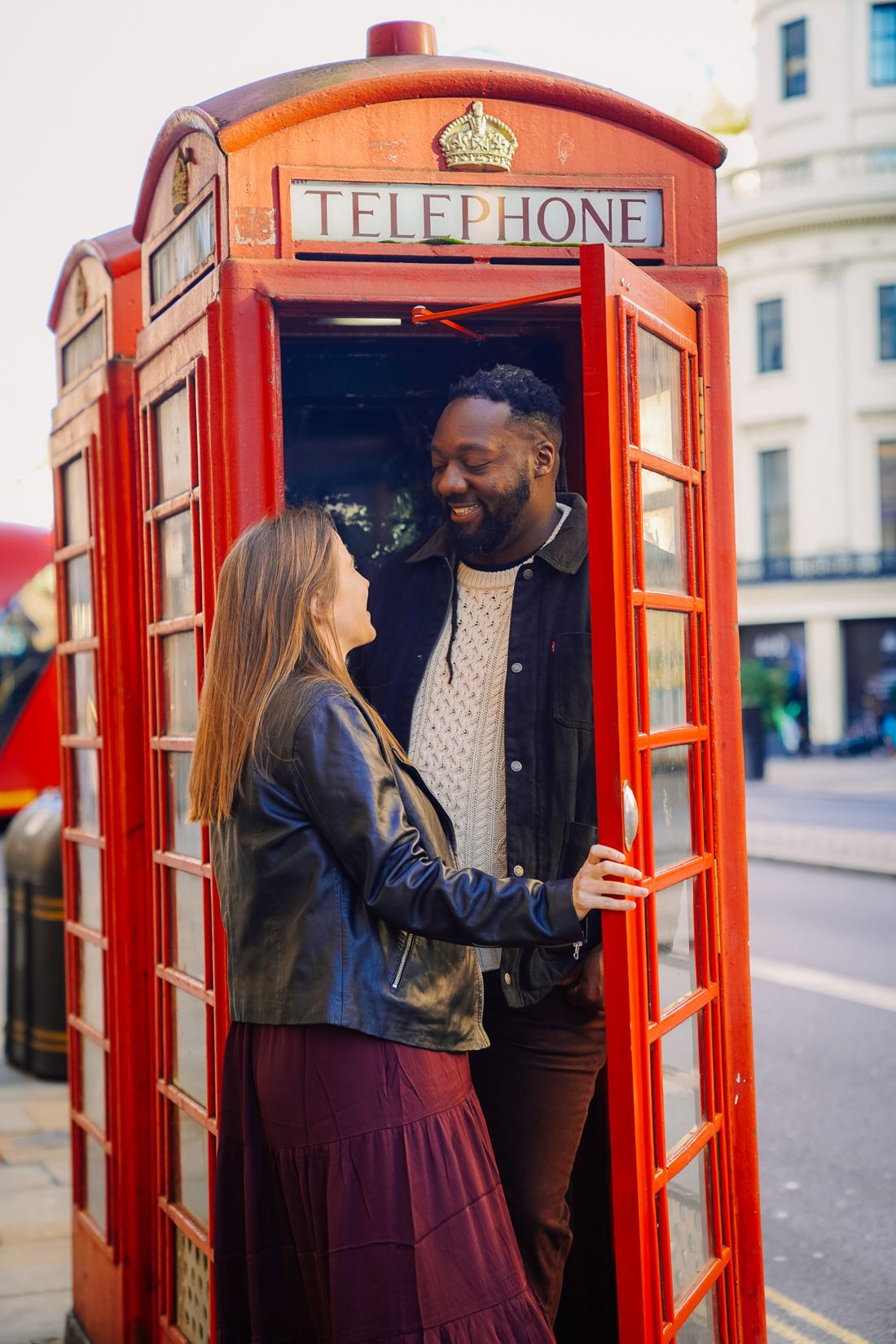 Couple smiling at each other in a red phone box