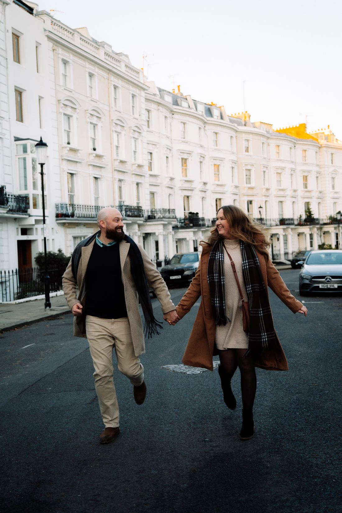 Couple running hand in hand down a white terraced street