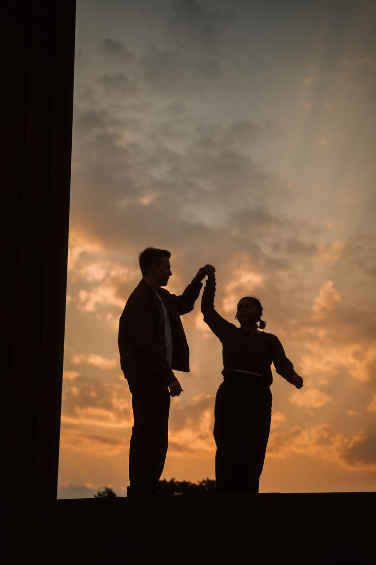 Couple dancing in silhouette against a sunset sky