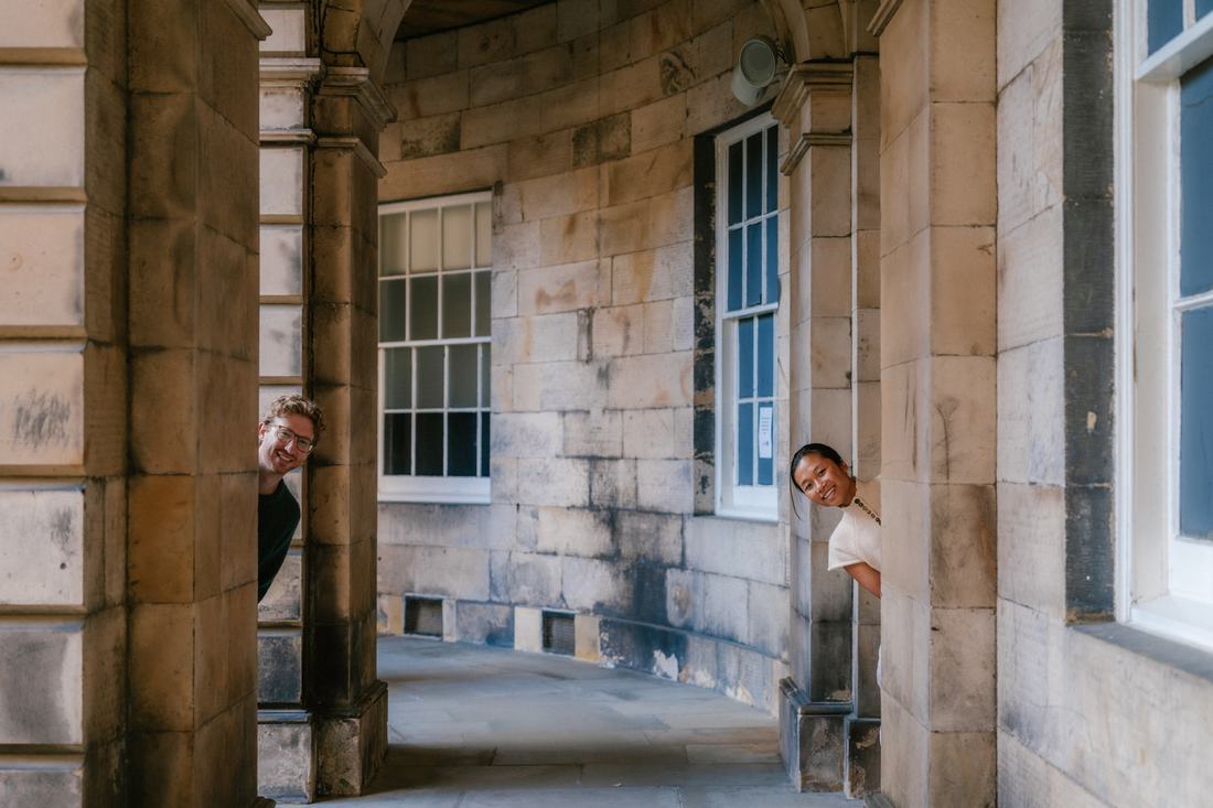Couple peeking around a stone pillar