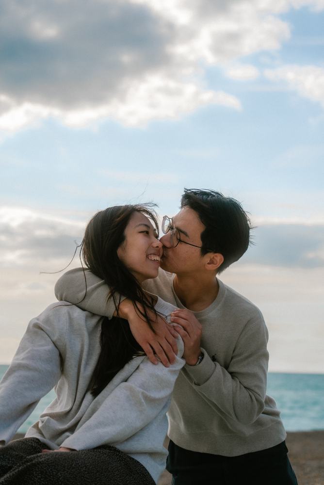 Couple kissing, laughing, by the sea