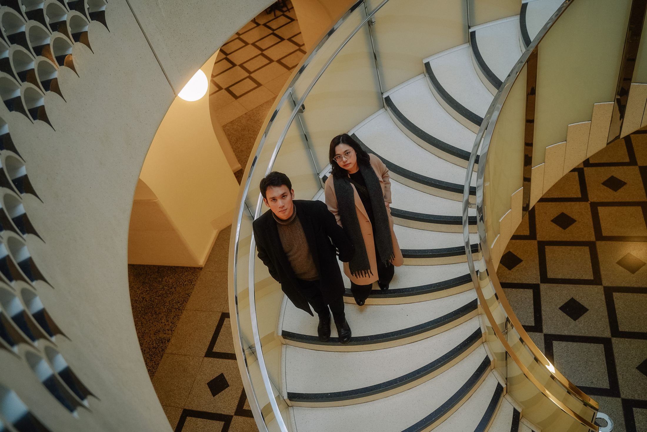 Couple looking up from a sweeping spiral staircase