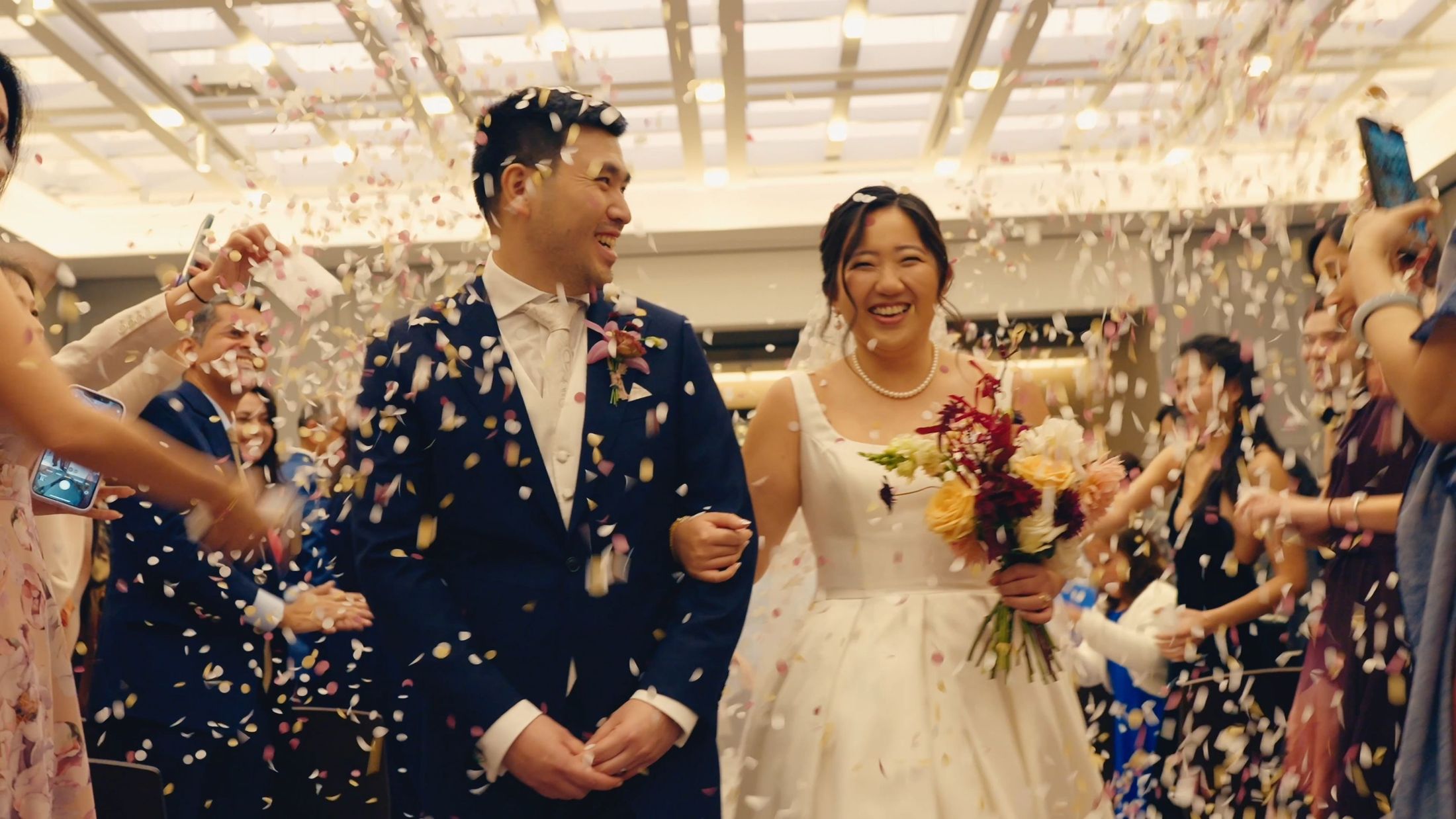 Bride and groom laughing through a shower of confetti