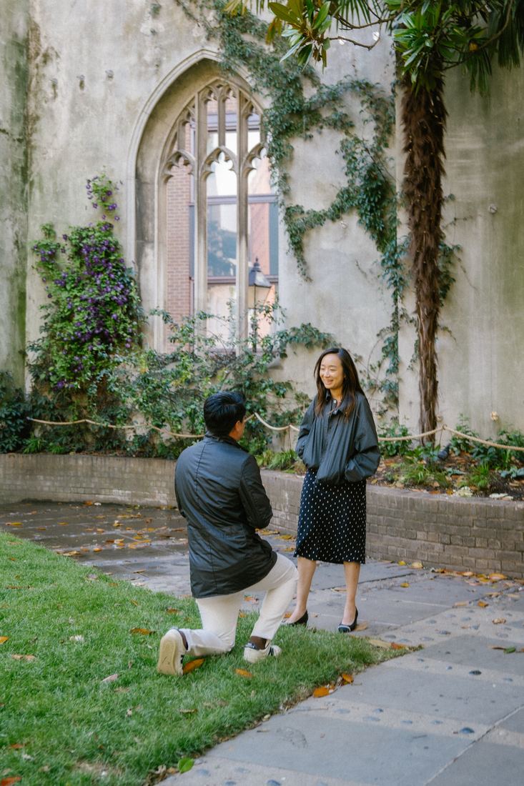 Man proposing on one knee in a ruined church garden