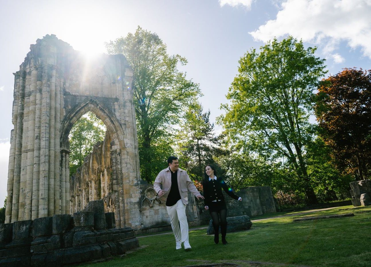 Couple walking past a ruined abbey arch in York